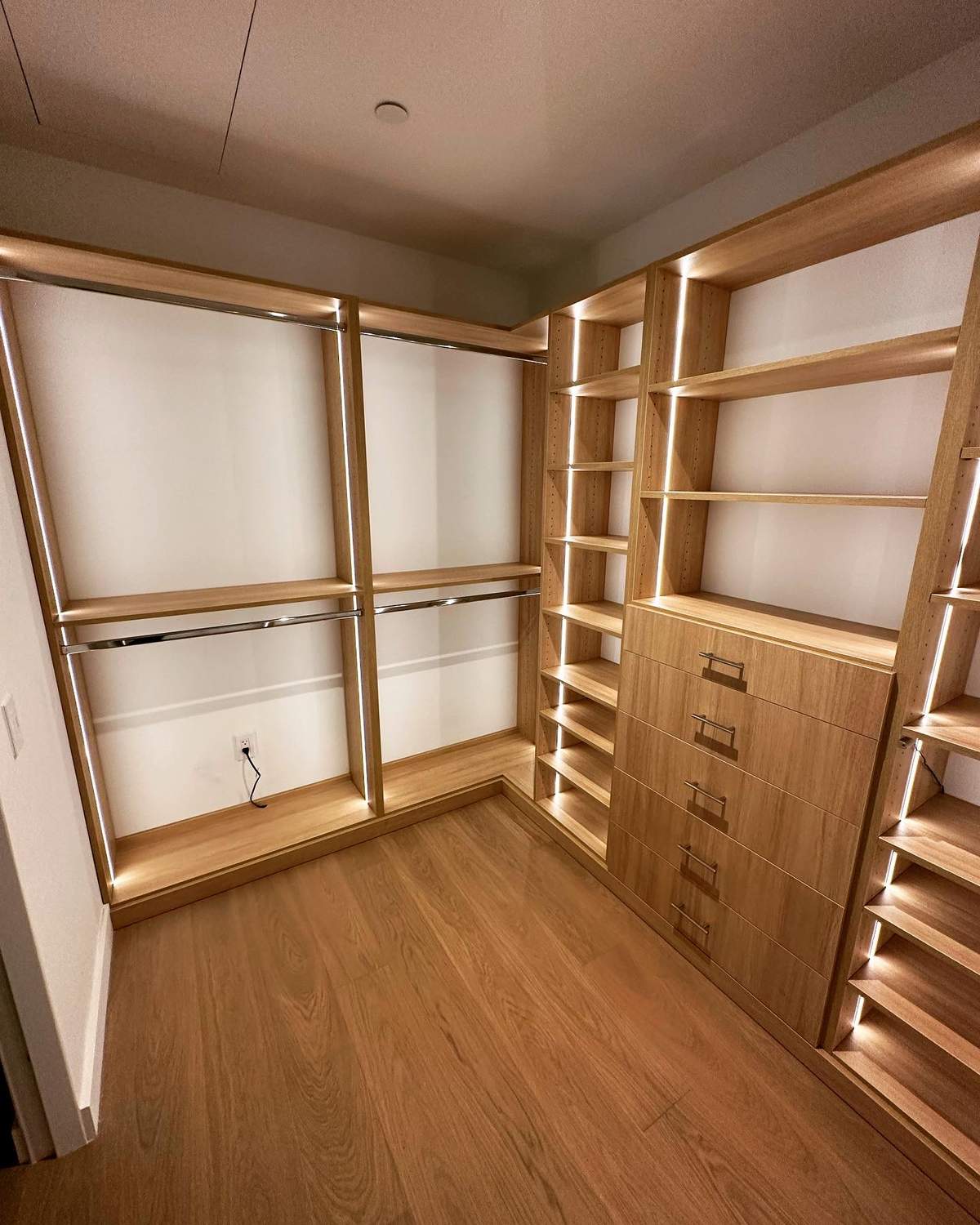 Custom walk-in closet with LED strip lighting, oak shelving, and built-in drawers