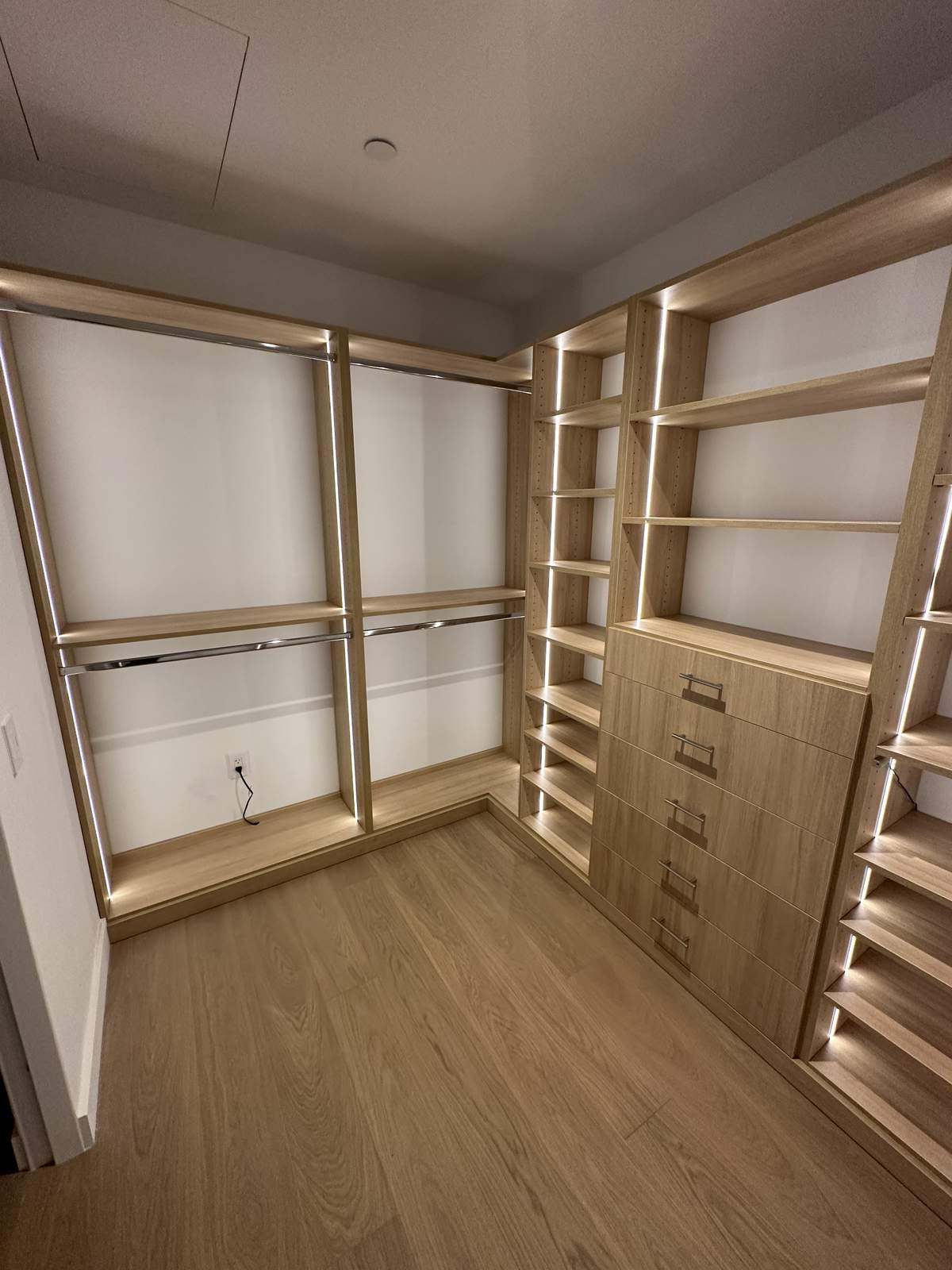 Walk-in closet with custom shelving, LED lighting, and valet rod