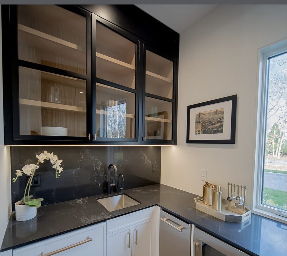 Modern butler's pantry with dark stone backsplash and black-frame glass cabinets
