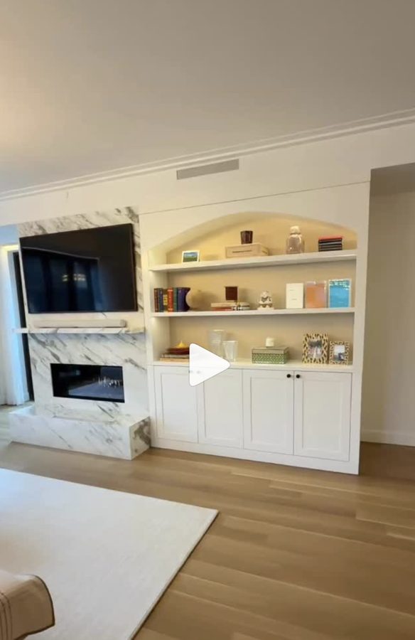 Custom living room with built-in entertainment center and marble fireplace surround