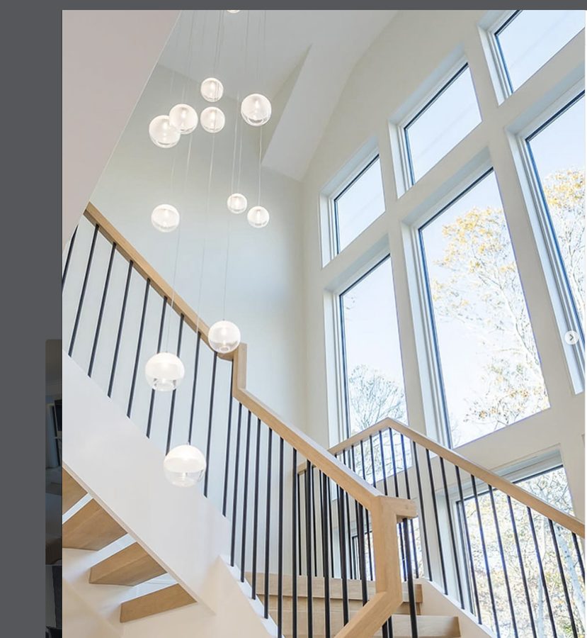 Custom statement staircase with oak treads, black metal balusters, and glass globe chandelier