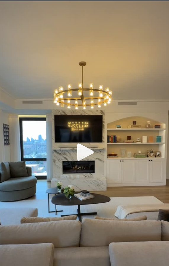 Upper West Side apartment living room with brass chandelier, marble fireplace, and built-in shelving