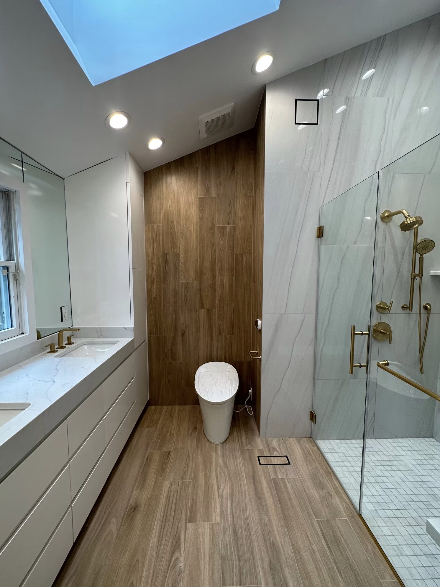 Full view of luxury bathroom renovation featuring custom walnut vanity, frameless glass shower, and marble tile by Lion Construction Management