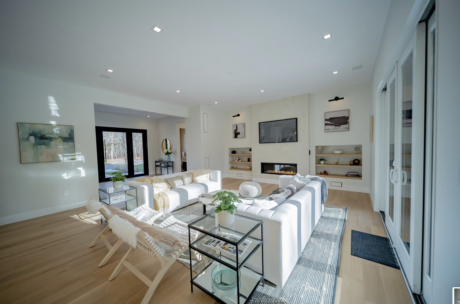 Living room with custom fireplace surround, built-in shelving, and hardwood floors in modern farmhouse
