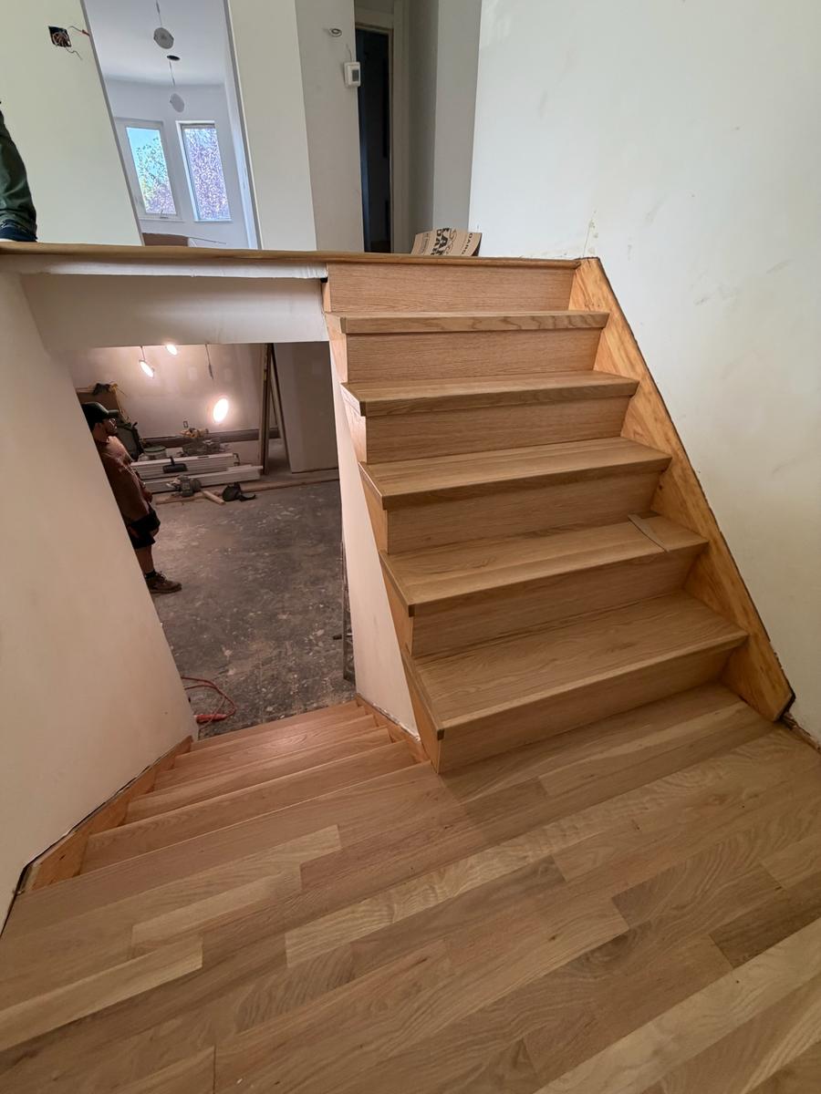 Oak stair tread installation viewed from above with worker
